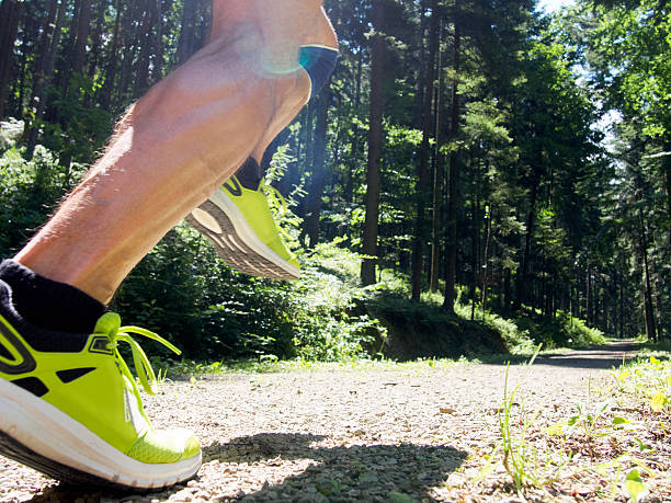 One mature woman, 40-45 years old, jogging in a forest outdoors, in nature. Wearing sport clothing in Spring.