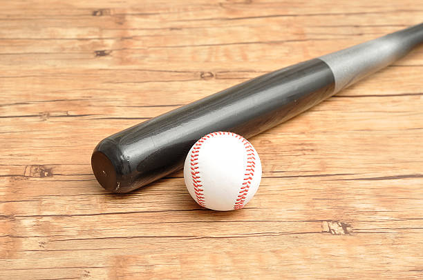 istock Baseball bat and ball isolated on a wooden background 637042096