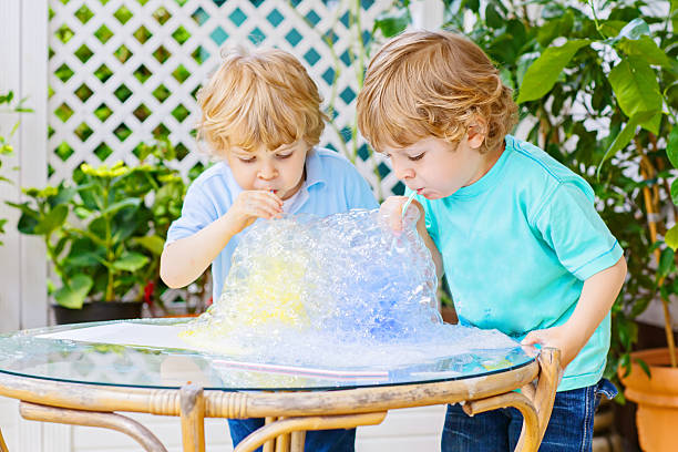 istock Two happy children making experiment with colorful bubbles 637044058