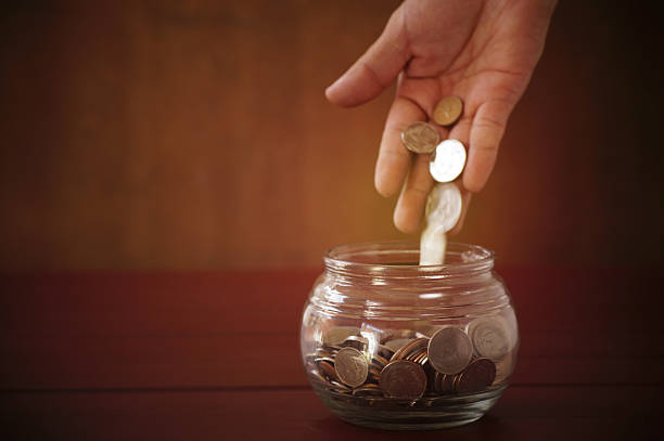 istock hand put money coins in bottle on wood table 637044914