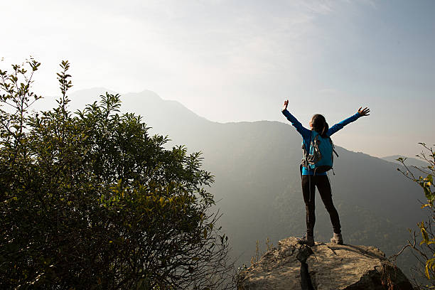 istock successful hiker open arms on mountain peak rock 637046698