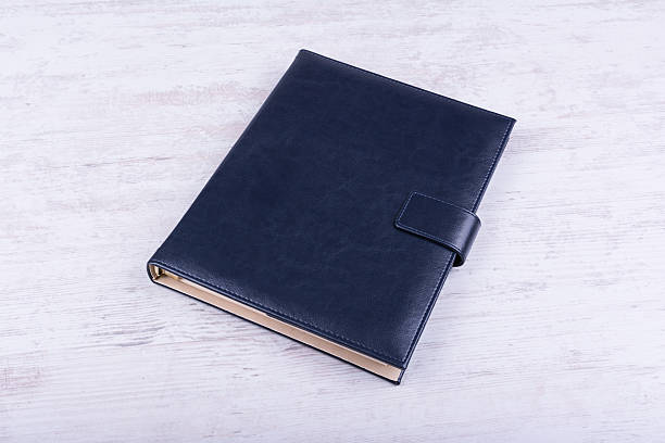 白い木製の背景に青い革のノートブック - leather folder ストックフォトと画像