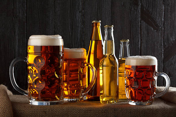 Assortment of beer glasses on table with burlap cloth, dark wooden background