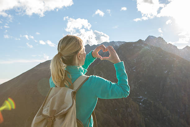 istock Young woman hiking on mountain top makes heart shape frame 637050268
