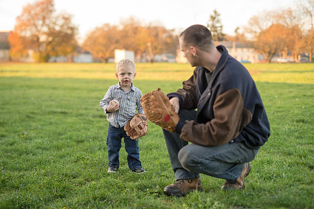 giovane padre che gioca con il figlio bambino in un parco - playing catch foto e immagini stock