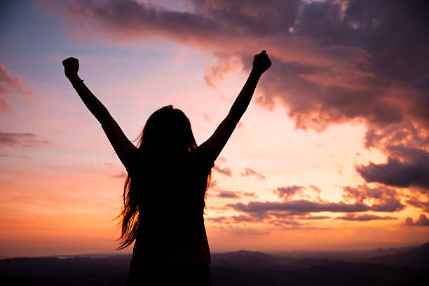 istock woman gesturing success - silhouette over evening sky 637058818