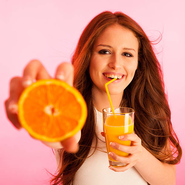 istock Woman drinking orange juice smiling showing oranges 637060088