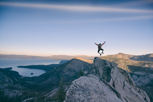 A man jumps for joy after successfully climbing a steep mountain cliff in Lake Tahoe, California