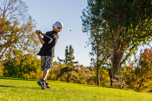 молодой мальчик играет в гольф. teeing во время заката - child swing swinging balance стоковые фото и изображения