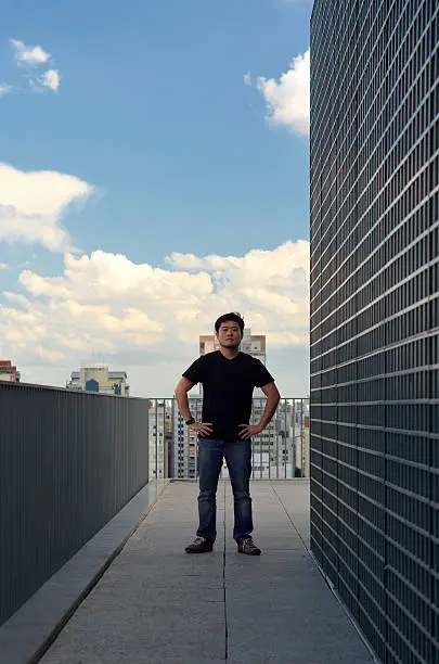 Asian man on a terrace with a urban landscape in the background