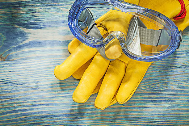 istock Protective leather gloves goggles on wooden board construction c 637071016