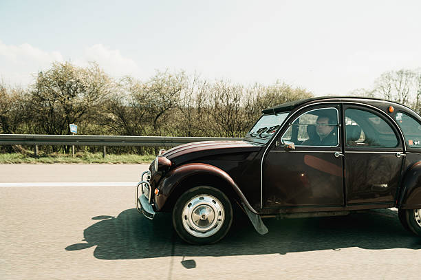 citroen 2cv vintage car driving on highway - deux chevaux stockfoto's en -beelden