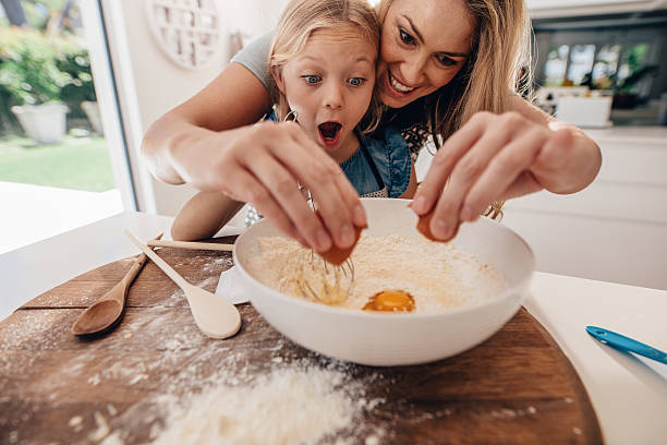 mother and daughter making dough in kitchen - mixing bowl imagens e fotografias de stock