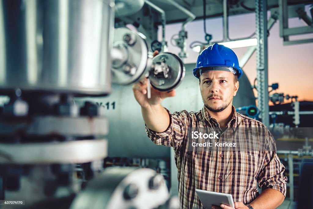 Uomo che usa una compressa presso l'impianto di trattamento del gas naturale - Foto stock royalty-free di Gas