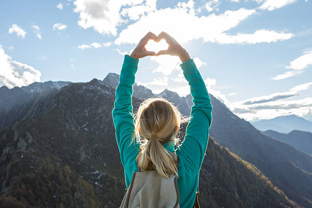 istock Young woman hiking on mountain top makes heart shape frame 637075664
