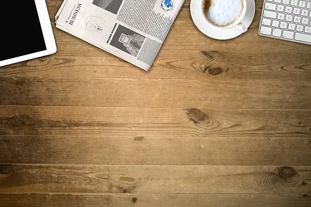 Photo of Daily newspaper and tablet pc on the wooden table.