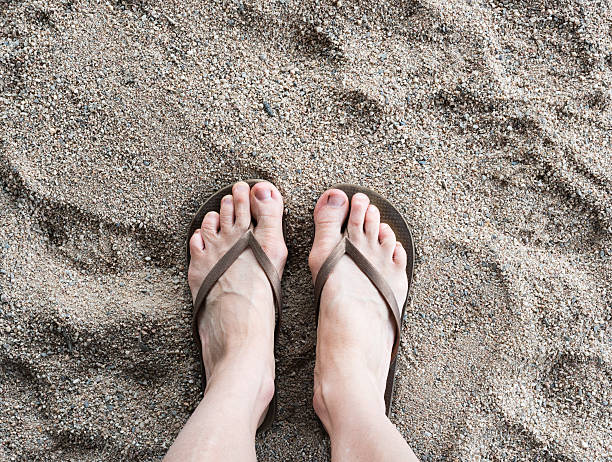 istock Feet in thongs on sand 637080916