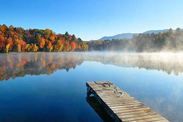 Autumn foliage Autumn foliage and fog lake in morning with boat dock new hampshire stock pictures, royalty-free photos & images