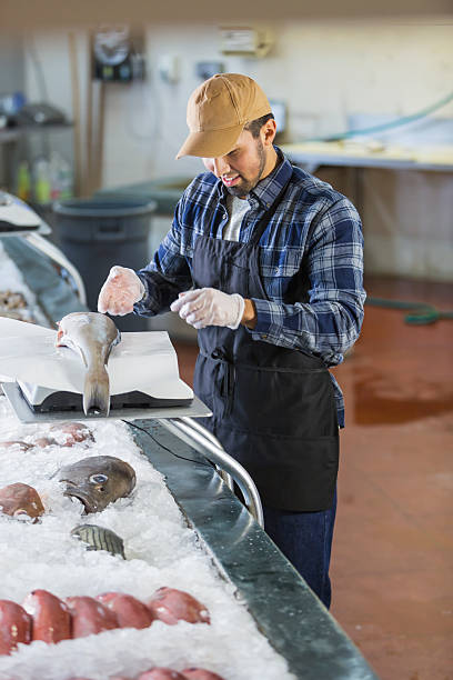 istock Hispanic man working in seafood market, weighing fish 637089230