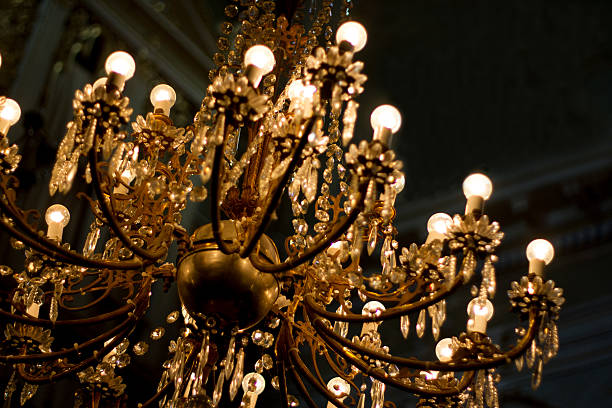 An ornate vintage illuminated gold chandelier against a black background (close-up). Some copy space available. Shot at a church in Italy.