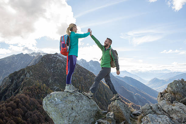 istock Hikers reaching mountain top celebrating with high five 637093498