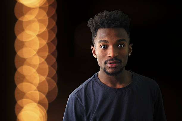 istock young man portrait dark shadow orange lights background 637100358