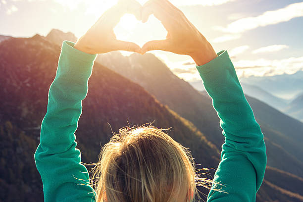 istock Young woman on mountain top makes heart shape finger frame 637100806