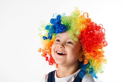 Cute little girl with clown wig is laughing.