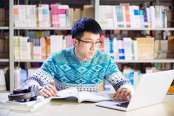 istock young asian man with laptop in library 637103374