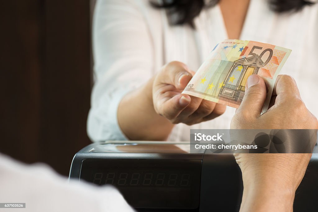 Young man paying cash at retail shop. Young man paying cash at retail shop. Customer and woman cashier in white dresses holding Euro money . Paying Stock Photo