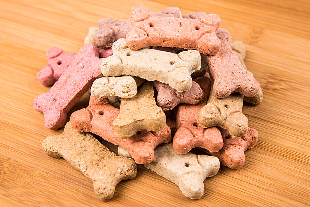 istock Stack of multicolored dog biscuits isolated on a wood background 637105192