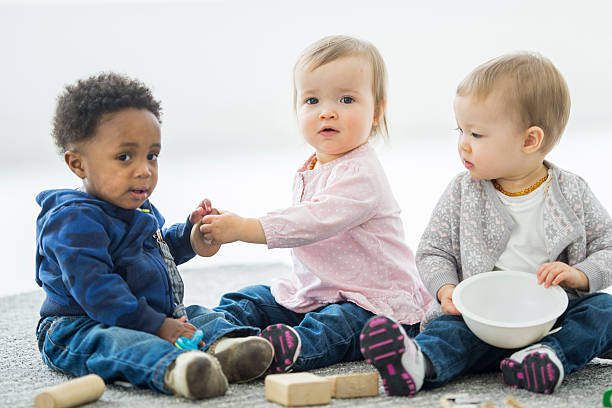 Babies Sharing Toys A multi-ethnic group of babies are playing with toys together at daycare. group of babies stock pictures, royalty-free photos & images
