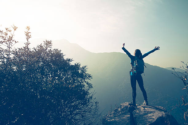 istock successful hiker open arms on mountain peak rock 637106996