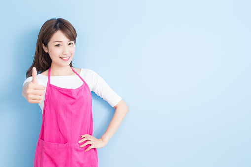 beauty housewife thumb up and smile to you isolated on blue background, asian