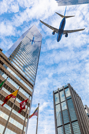 Plane reflecting on modern glass building facade while flying through the sky, Hong Kong island. Concept of transport, travel and business. Urban Central district cityscape.