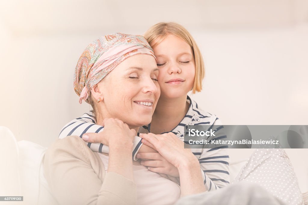 Child embracing ill mother Small caring child embracing her ill mother with headscarf Cancer - Illness Stock Photo