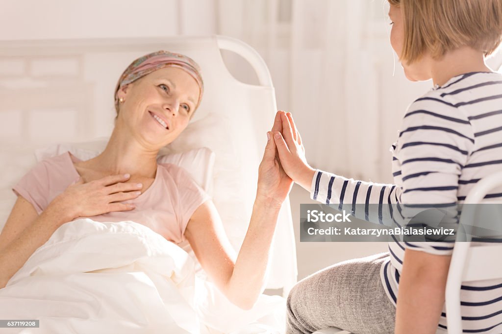 Cancer woman touching child's hand Cancer woman lying in hospital bed, touching child's hand Leukemia Stock Photo