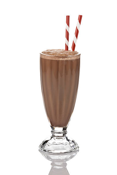 Chocolate Milkshake on white backdrop. Classic glass of chocolate milkshake standing on reflective white backdrop. There are two old-fashioned red-and-white straws standing in the glass. Visible reflection of the glass on the foreground.  DSRL studio photo taken with Canon EOS 5D Mk II and Canon EF 70-200mm f/2.8L IS II USM Telephoto Zoom Lens chocolate shake stock pictures, royalty-free photos & images