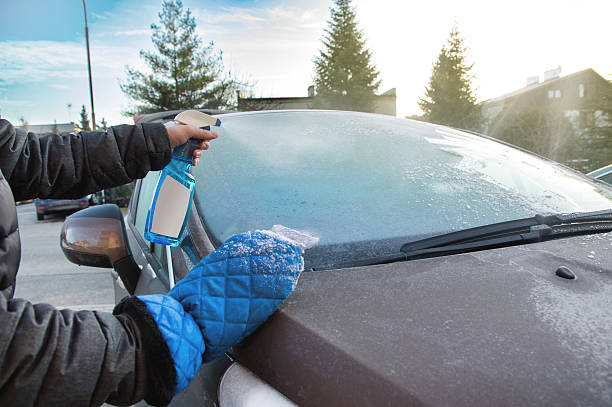 男は霜を除去するためにデフロスタースプレーを使用しています - frozen windshield cold car ストックフォトと画像