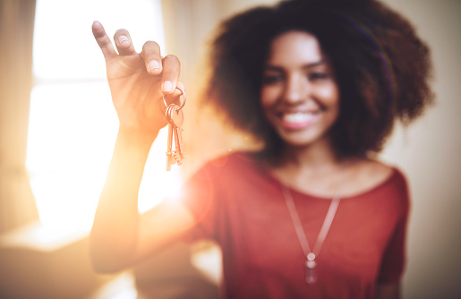 Portrait of a young woman holding up the keys to a new home