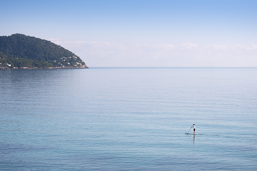 Woman Stand Up Paddeling SUP in the wide calm Ocean Nikon D800e. Converted from RAW. Lots of room for copy.