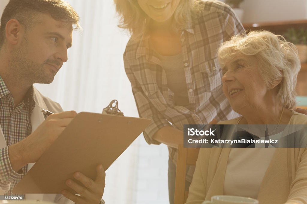 Mature woman talking with doctor Mature woman talking with doctor during private home visit Adult Stock Photo