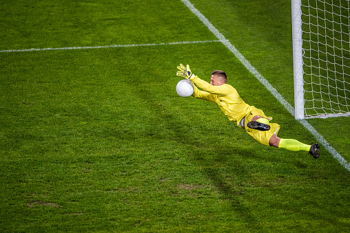 Soccer goalie diving to block the ball.