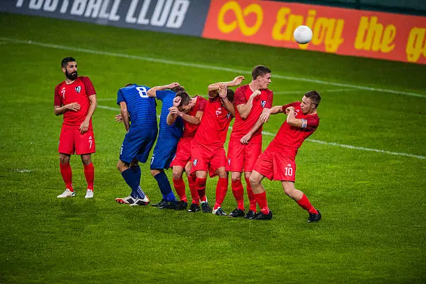 Male football players defending during free kick goal.