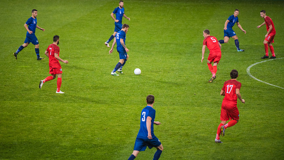 Male football players challenging for ball on field during match.