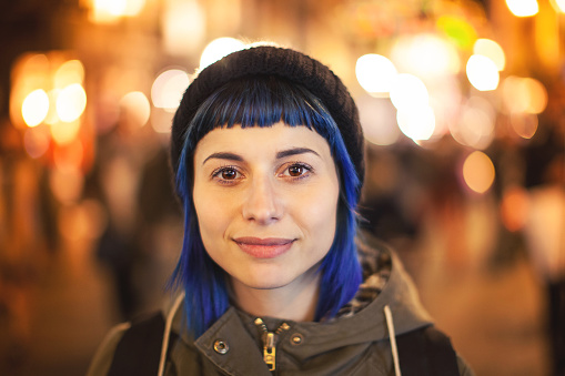 Young woman bluehair walking through citylight