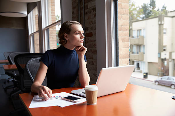 istock Thoughtful Businesswoman Working On Laptop By Window 637153802