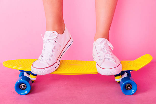 Conceptual shooting of girl's feet standing on the skateboard