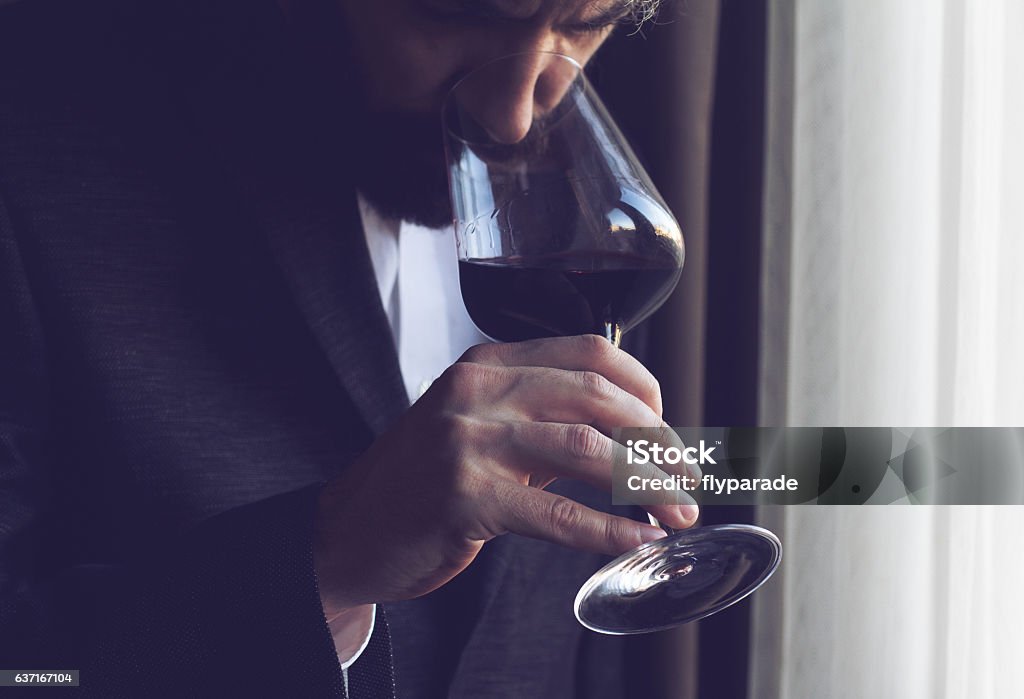man tasting a glass of red wine horizontal close up of a Caucasian man with beard, black suit and white shirt tasting a glass of red wine Wine Stock Photo