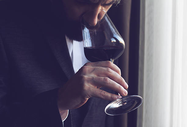 man tasting a glass of red wine horizontal close up of a Caucasian man with beard, black suit and white shirt tasting a glass of red wine sommelier photos stock pictures, royalty-free photos & images